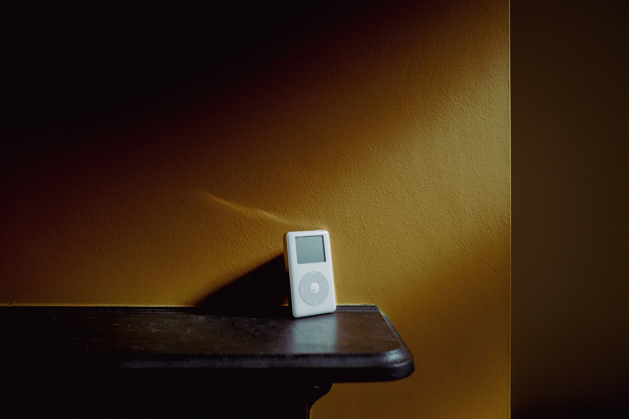 4th generation iPod with click wheel against a yellow wall